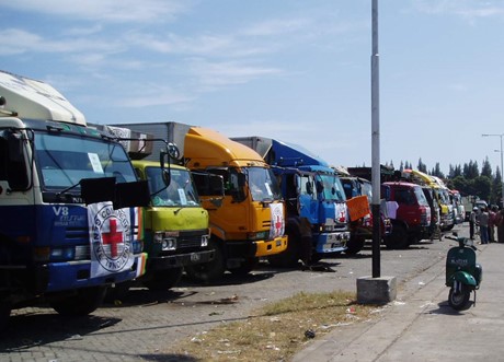 An image of rented lorries with Red Cross emblem flags on the front of the vehicles